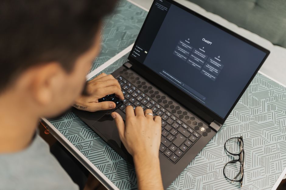 A small business owner smiling at her laptop screen, which displays a friendly AI chatbot assisting a customer.