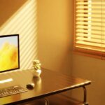 A well-organized small home office desk with a laptop, external monitor, and a comfortable keyboard, showing efficient use of space.