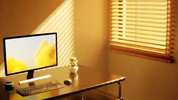 A well-organized small home office desk with a laptop, external monitor, and a comfortable keyboard, showing efficient use of space.
