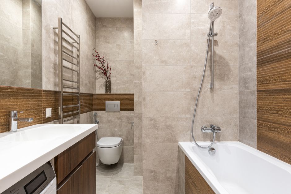 A small, well-organized bathroom vanity with a compact caddy holding a spray cleaner, a small scrub brush, and folded clean towels, illustrating localized cleaning supplies.