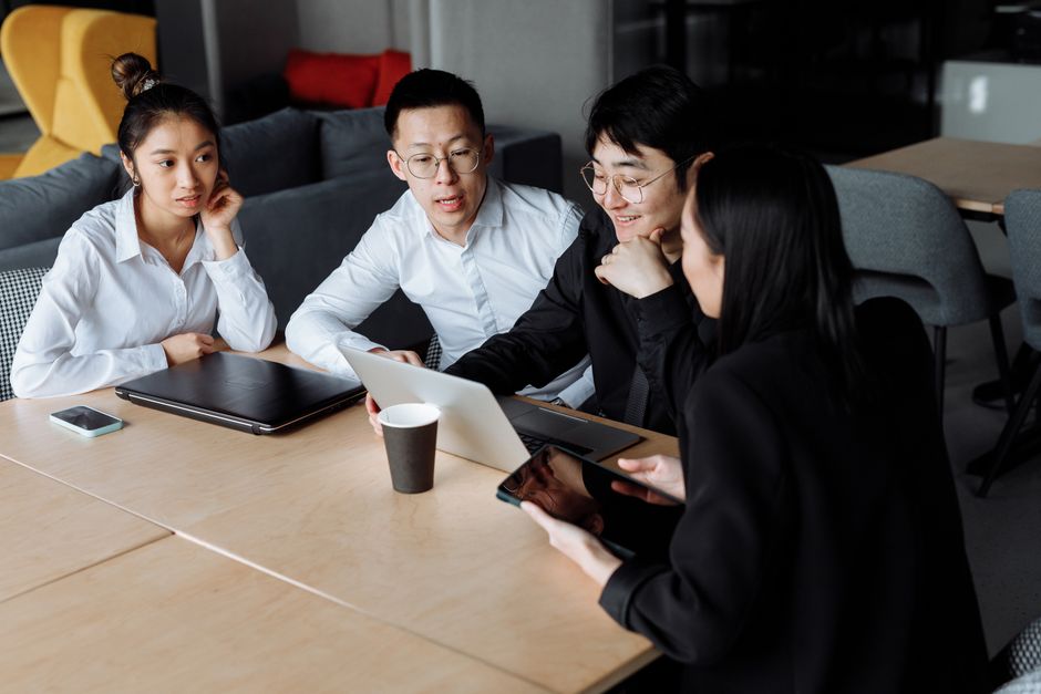 A small team of professionals in a modern office having a focused discussion around a table, symbolizing collaboration on AI policy.