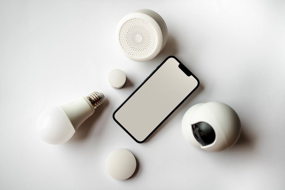 A modern living room with smart lighting showing warm tones, a Google Nest Hub on a side table, and a smart plug in the background.