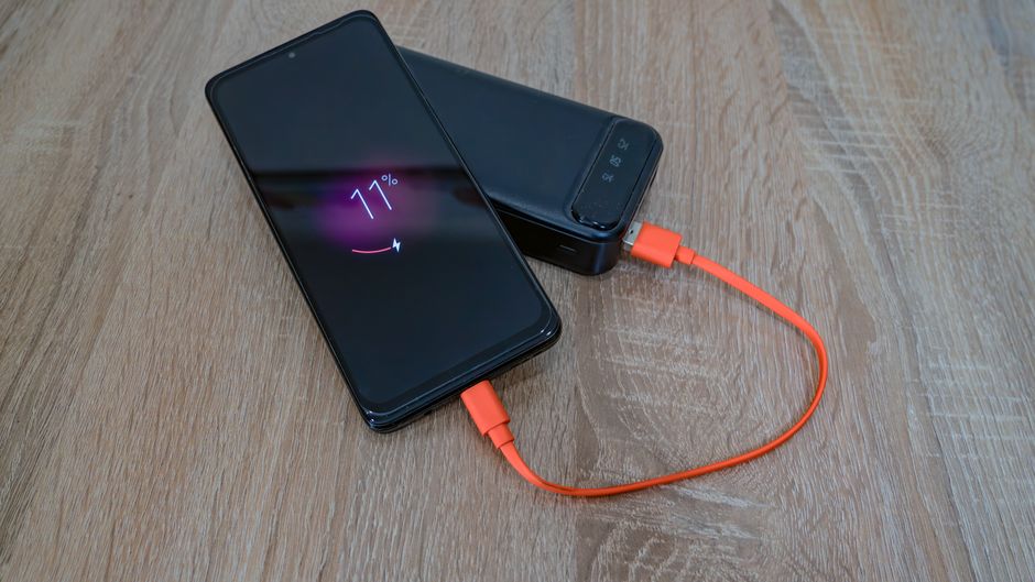A smartphone connected to a charging cable and a power adapter, illustrating battery charging.