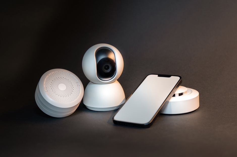 An old smartphone positioned on a shelf, clearly acting as a home security camera watching a living room.