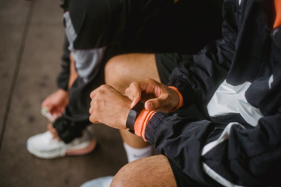 A student running outdoors in a city park, their smartwatch clearly visible tracking their workout metrics.
