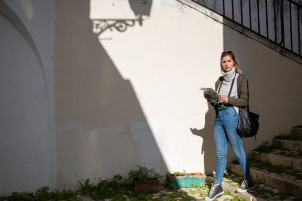A solo female traveler in a bustling European square, looking at a map with a thoughtful expression, symbolizing travel planning dilemmas.