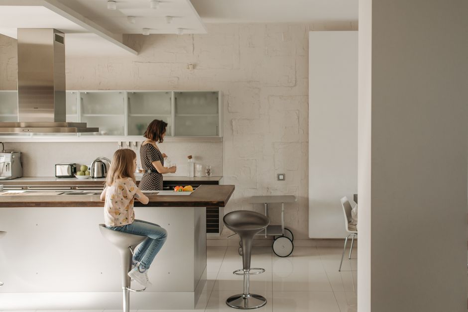 A family cooking together in a bright, modern apartment kitchen, showing ample counter space and a dining area.