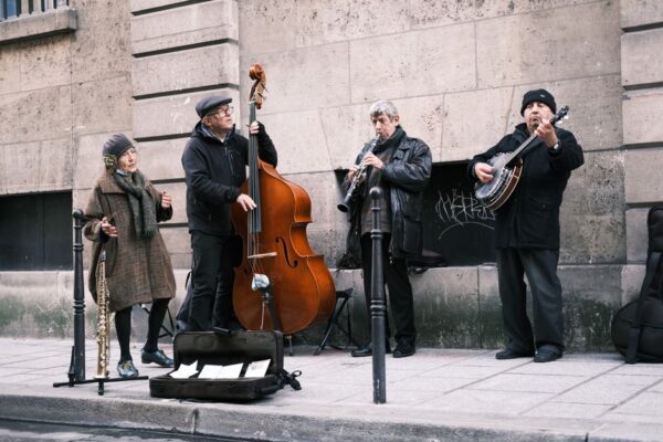 A street musician playing an accordion on a cobblestone street in Paris, with a small crowd gathered around, enjoying the performance.