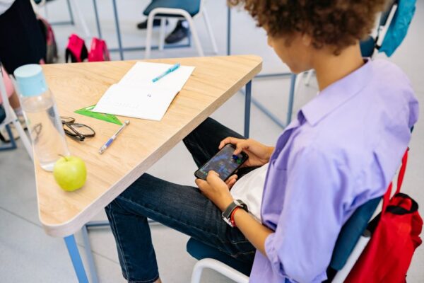 A student happily engaged with a language learning game on a tablet, showing a mix of text and colorful graphics.