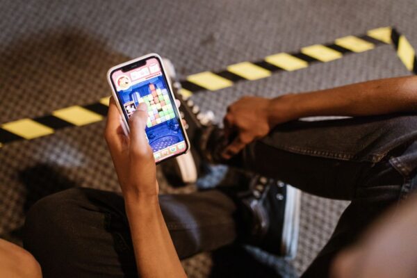 Student focused on a mobile puzzle game on a bus, with city lights blurred in the background, representing a typical commute.