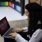 A student in a modern library setting, using a laptop, with abstract AI interface elements overlaid, symbolizing the integration of AI tools for study.