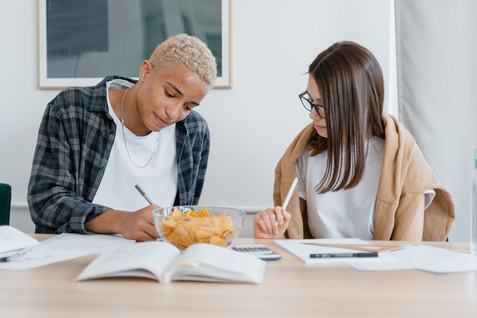 A student focused on textbooks with a spread of brain-boosting snacks like berries, dark chocolate, and avocado toast nearby.