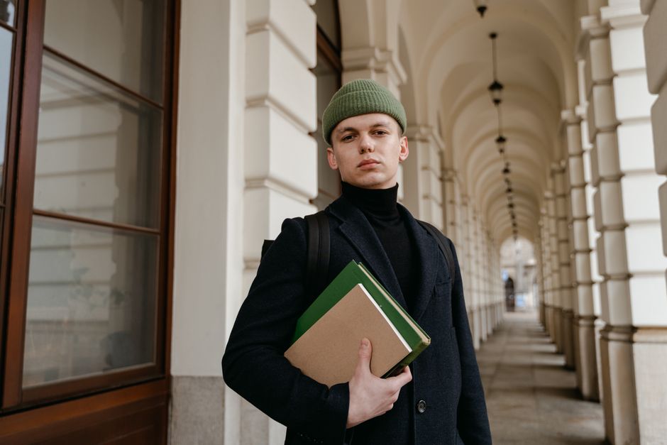 A student with a backpack on a busy street, embodying practical street style with neutral clothing and comfortable, fashionable sneakers.