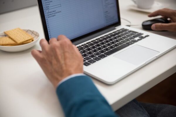 A student in a library setting, focused on a laptop screen displaying a Google Sheet, suggesting a common scenario for spreadsheet challenges.