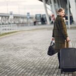 A person easily pulling a sleek, hard-shell carry-on suitcase through a bright, modern airport terminal, demonstrating effortless travel.