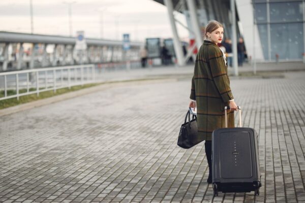 A person easily pulling a sleek, hard-shell carry-on suitcase through a bright, modern airport terminal, demonstrating effortless travel.