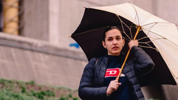 A stylish person in a trench coat walking through a rainy city street, protected from the elements.