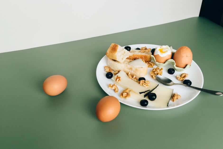 An overhead shot of a table displaying various convenient protein sources like almonds, canned tuna, hard-boiled eggs, and cottage cheese.