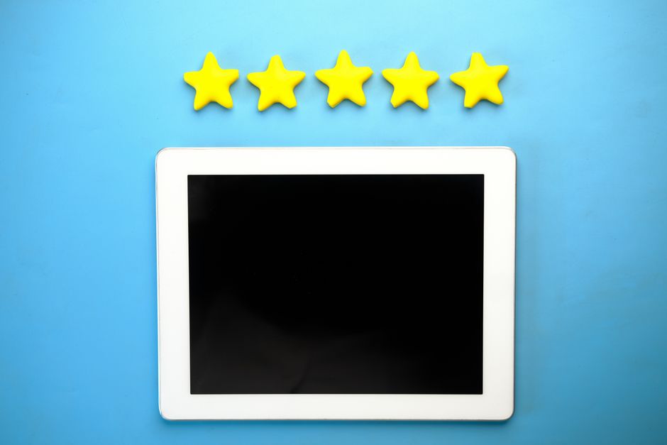 A close-up of a tablet screen displaying various age rating icons like PEGI and ESRB, with parental hands hovering.