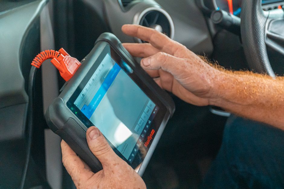 A technician using specialized tools to test the functionality and ports, including a USB-C, of a refurbished tablet in a repair workshop.