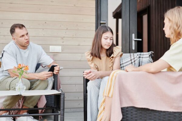 A parent and teenager having an open conversation about AI tools, with a tablet showing various apps.