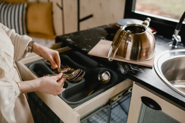 A neatly organized, very small apartment kitchen with wall-mounted shelves and magnetic knife strip, showing efficient use of space.