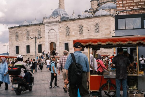 A tourist firmly but politely declining a street vendor trying to sell a bracelet, emphasizing how to avoid the 'found' ring or bracelet scam.