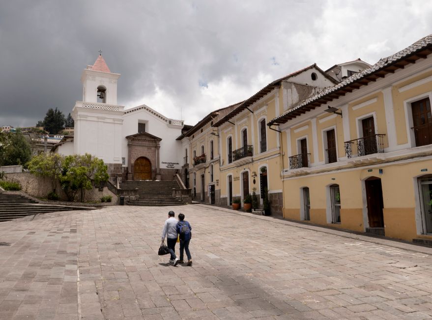 Tourists walking along a narrow cobblestone street lined with vibrant colonial buildings in a historic South American city, suggesting popular and safe tourist areas.