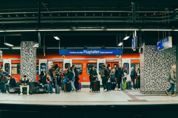 Travelers waiting for an airport express train at a modern, well-lit platform with luggage.