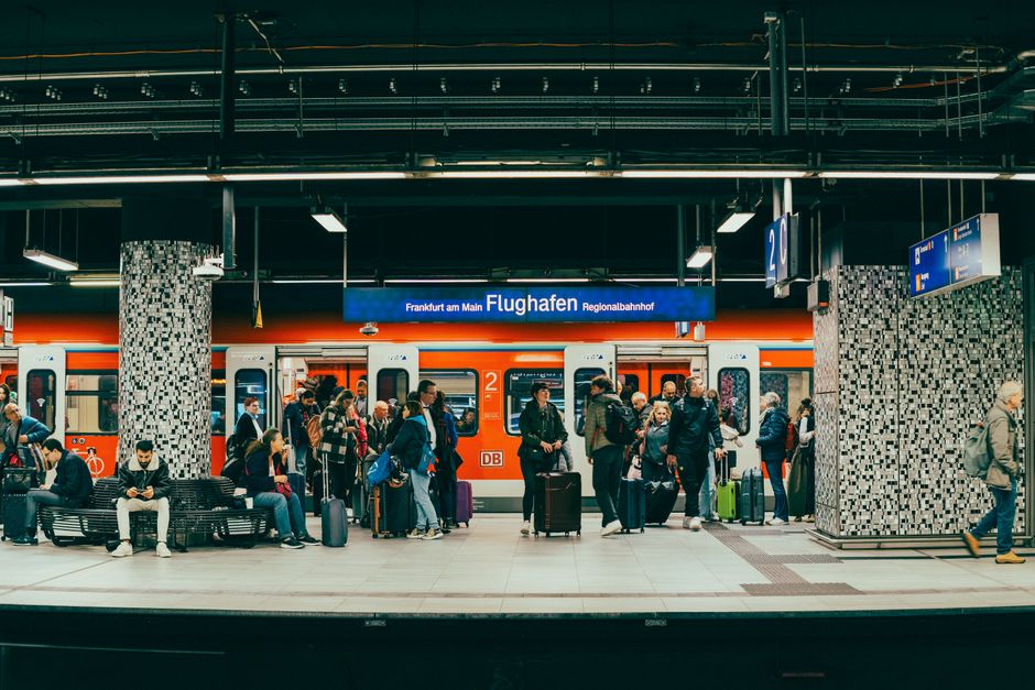 Travelers waiting for an airport express train at a modern, well-lit platform with luggage.