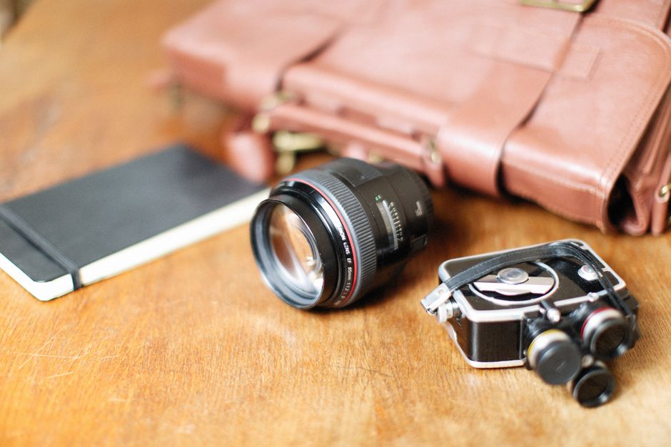Flat lay of various city travel bag types and their common contents like passport, wallet, phone, and sunglasses, laid out neatly for comparison.