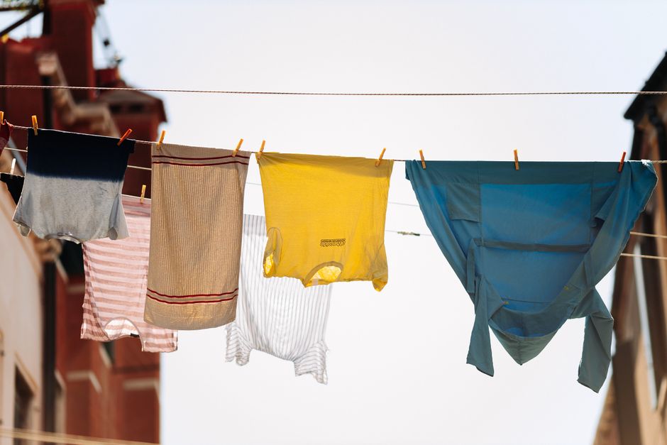 Quick-drying activewear hanging on a flexible travel clothesline strung across a hotel room window.