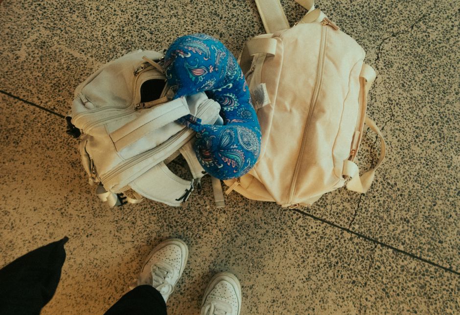 A traveler wearing slip-on sneakers easily navigating an airport terminal, with luggage beside them, illustrating ease of movement.