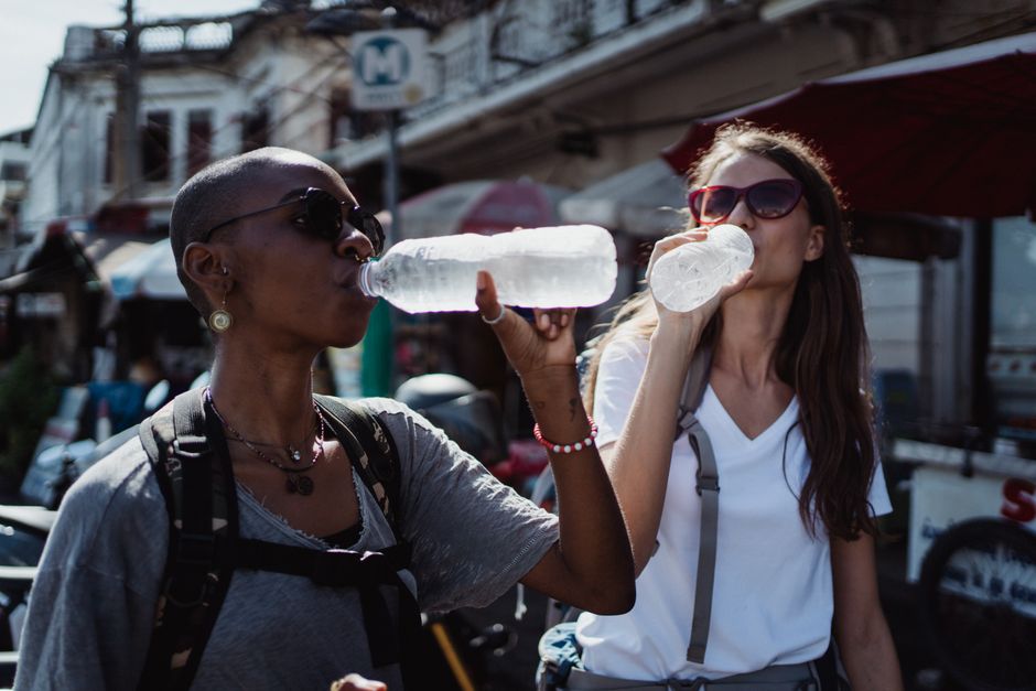 Traveler in a bustling South American market, holding a sealed bottle of water and looking at fresh fruits, highlighting safe hydration.