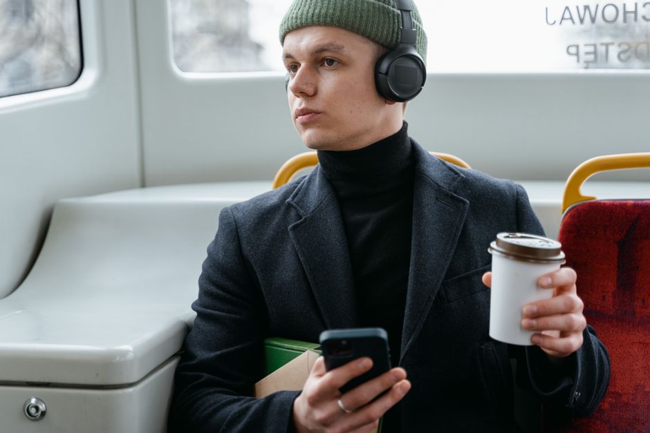 A person comfortably seated on a train, wearing a plaid shirt over a base layer, looking out the window, illustrating train travel comfort.