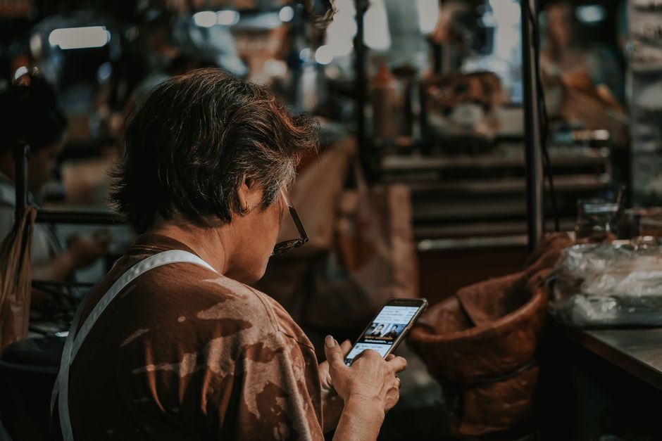 A traveler in a vibrant South American marketplace holding a smartphone displaying real-time language translation, facilitated by AI for seamless communication.