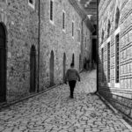 A person in comfortable sneakers walking down a sun-drenched cobblestone street in a European city, clearly enjoying their stride.