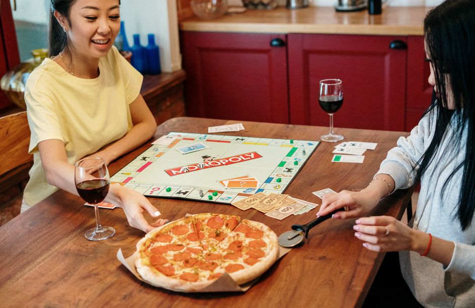 A couple sitting at a table, intensely focused on a board game, with game pieces and cards spread out.