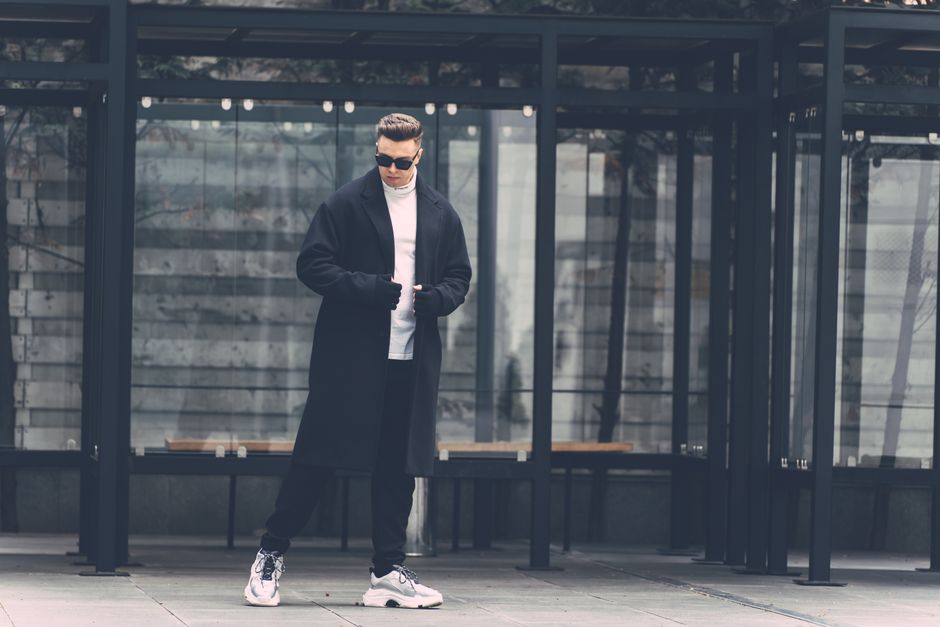 A person elegantly layered for cold weather, walking confidently through a vibrant European city street.