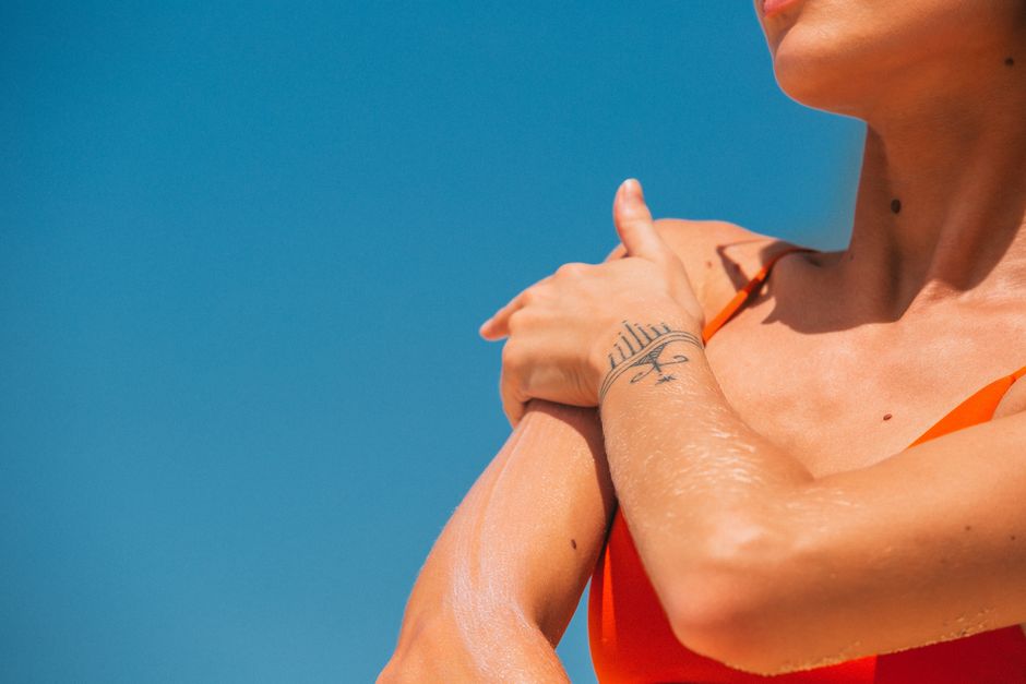A small, discreet UV sensor patch applied to skin on an arm, indicating sun exposure levels in a clear, digital display.