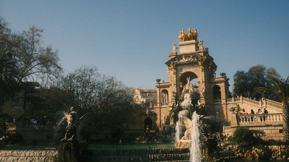A scenic view of the monumental fountain in Parc de la Ciutadella, Barcelona, with people enjoying the park in the foreground.