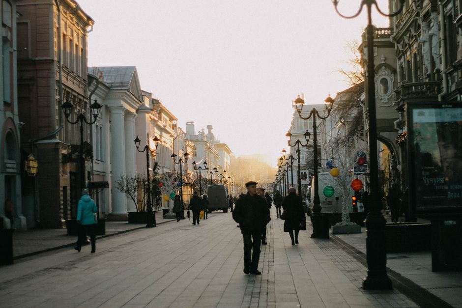 A vibrant street scene in a European city, with people walking, historic buildings, and cafes, emphasizing walking as a mode of travel and exercise.
