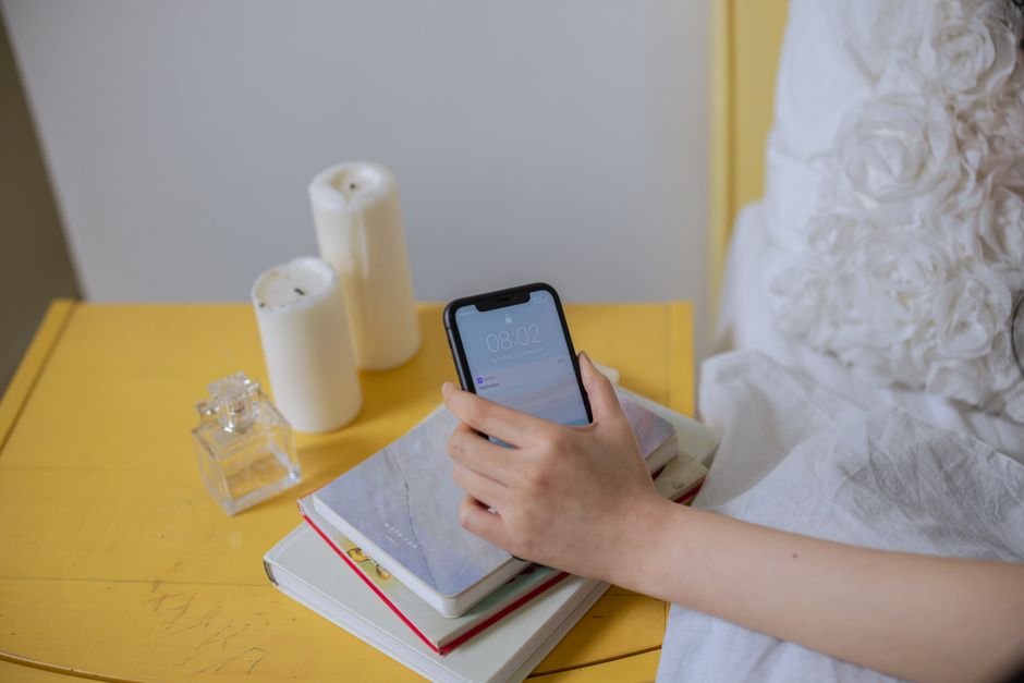 A collection of popular sleep tracking wearables like an Oura Ring, Apple Watch, and Garmin watch resting on a wooden nightstand next to a glass of water, symbolizing the tools for sleep tracking.