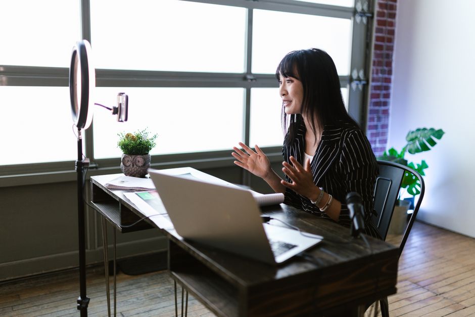 Close-up of a well-arranged desk with a high-quality external webcam mounted on a monitor, a desktop USB microphone, and a small LED panel light.