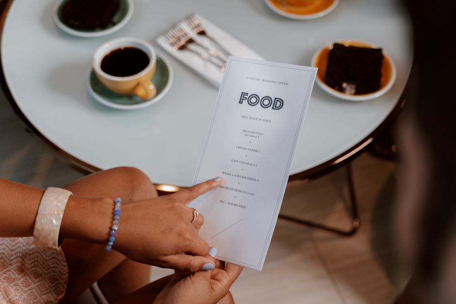 A woman in a stylish restaurant looking at a digital menu on a tablet, thoughtfully considering her options for a healthy meal.