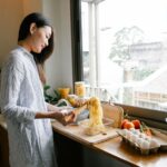 A woman smiling while quickly assembling ingredients for dinner in a clean, modern kitchen.