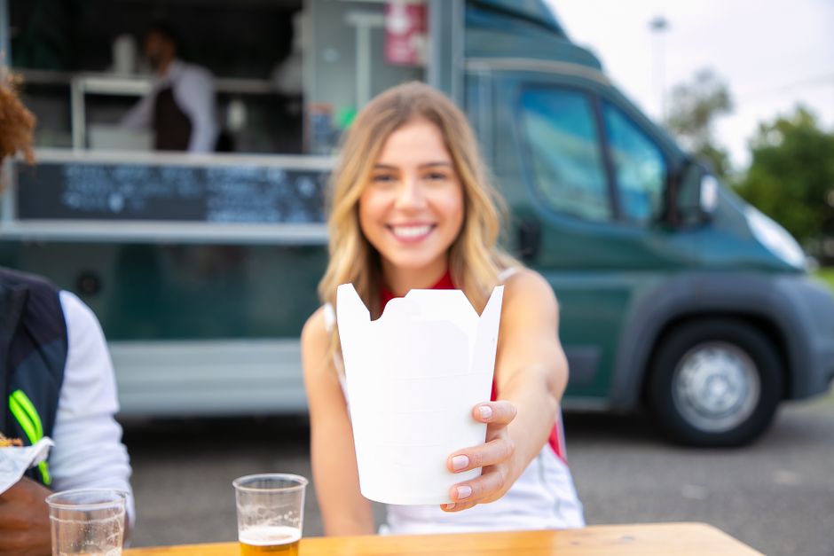 A solo woman smiling while enjoying a local street food dish in a lively market, highlighting the joys of spontaneous, flexible travel experiences.