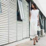 Woman wearing a simple, elegant neutral-toned outfit, walking purposefully in an urban setting, embodying quiet luxury style.