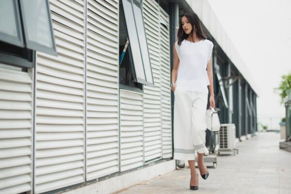 Woman wearing a simple, elegant neutral-toned outfit, walking purposefully in an urban setting, embodying quiet luxury style.