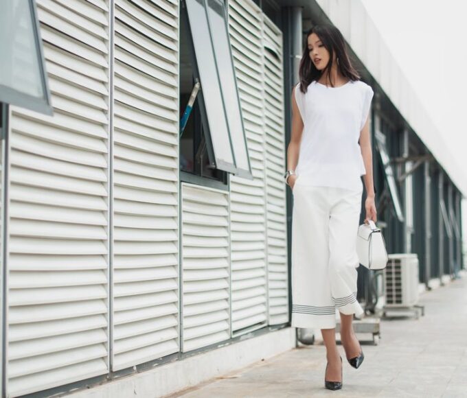 Woman wearing a simple, elegant neutral-toned outfit, walking purposefully in an urban setting, embodying quiet luxury style.